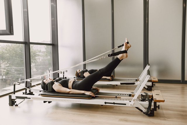 Zwei Frauen trainieren auf Reformer-Geräten im Pilates Studio